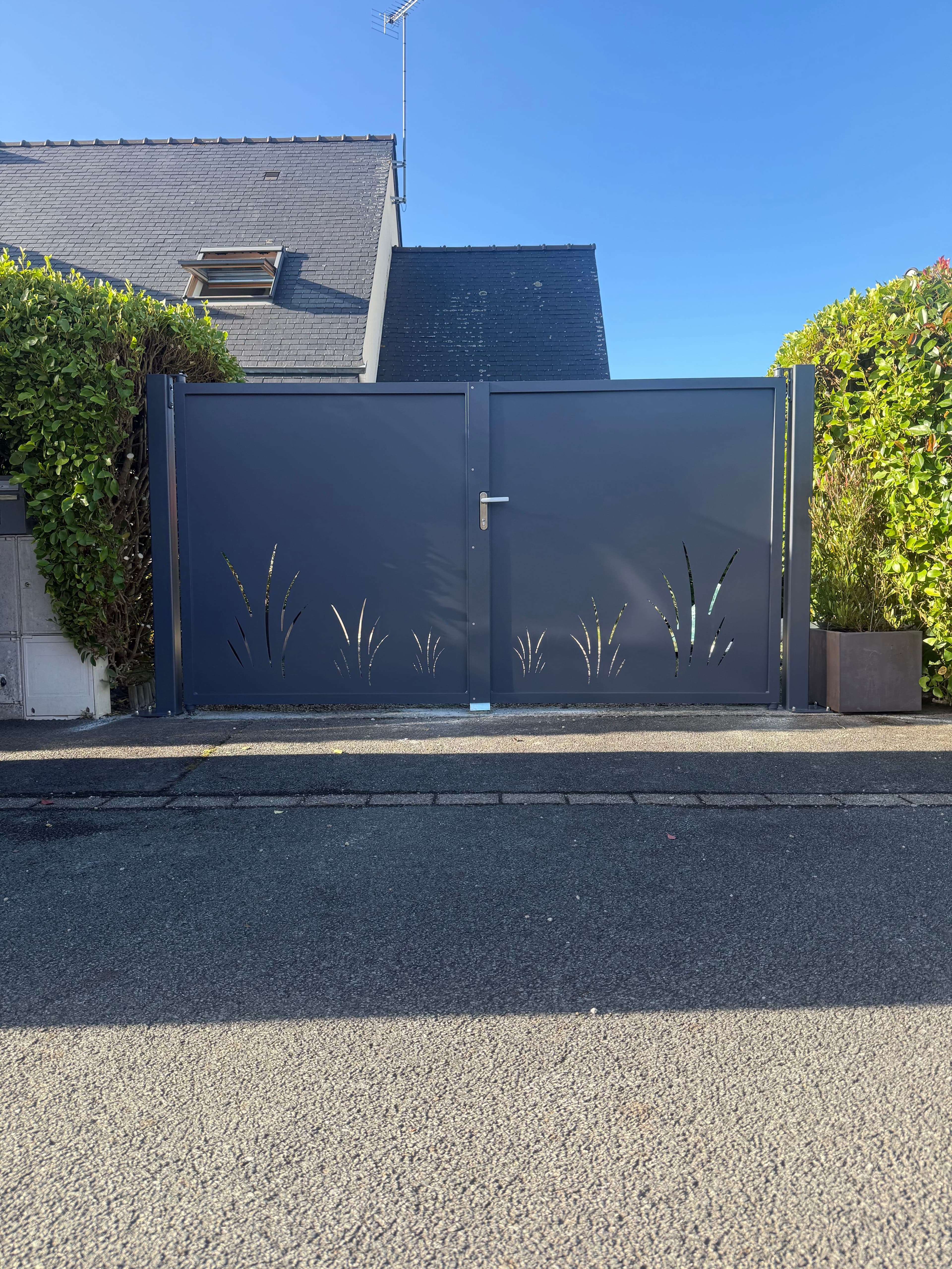 Portail aluminium moderne avec découpe décorative effet végétal.